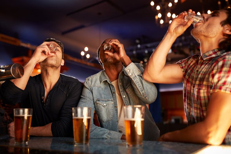 Three guys drinking shots.