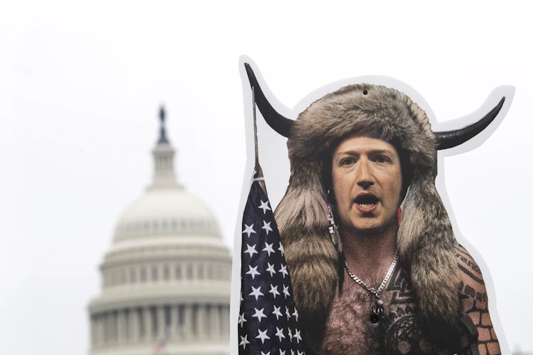 A cutout display of a man wearing a fur headdress with bison horns and holding a U.S. flag is positioned in front of the US Capitol building