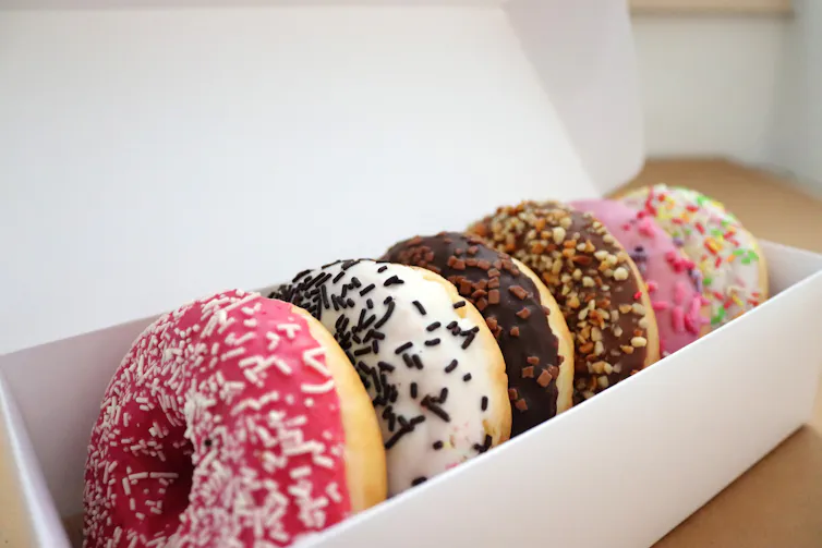 Des beignets avec des éclats de chocolat dans une boîte blanche