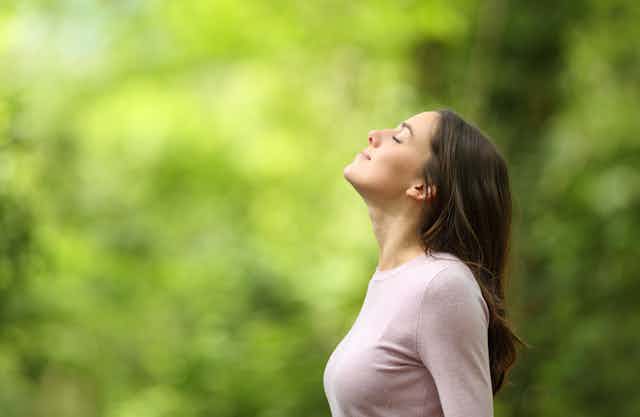 Profile of a relaxed woman breathing fresh air in a green forest.