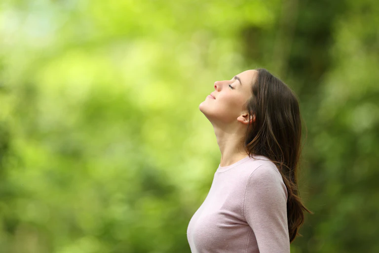 Profile of a relaxed woman breathing fresh air in a green forest.