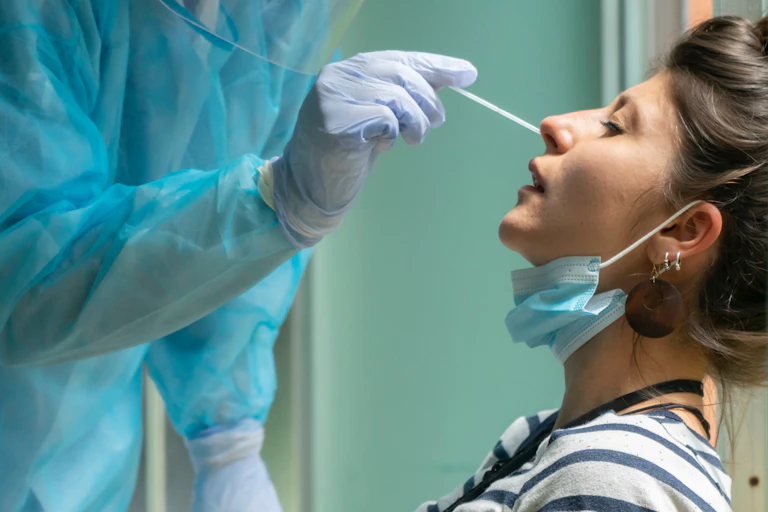 Un professionnel effectue un prélévement dans le nez d’une femme grâce à un évouvillon