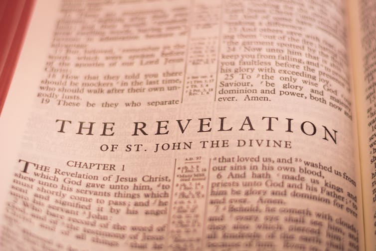 a photograph of a Bible page reading THE REVELATION OF ST. JOHN THE DIVINE