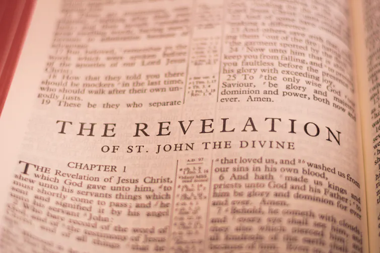 a photograph of a Bible page reading THE REVELATION OF ST. JOHN THE DIVINE