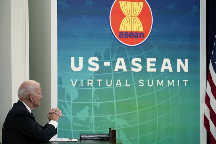 A man in a suit sits in front of a blue/green screen that reads US-ASEAN virtual summit