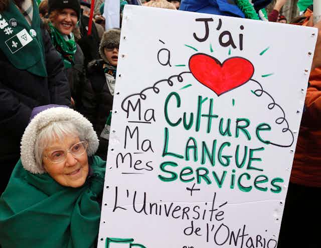 Une femme âgée brandissant une pancarte.