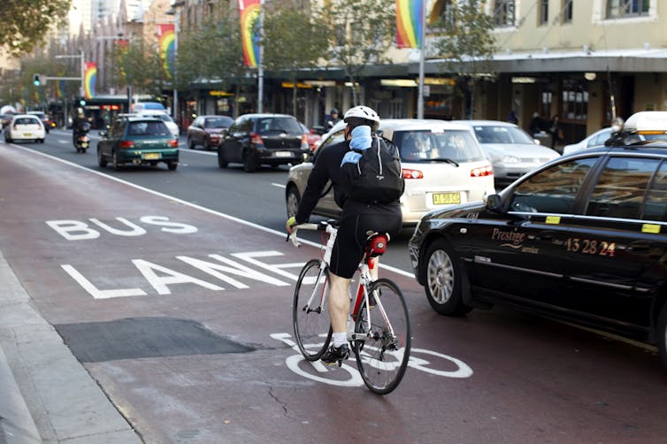 A cyclist is nearly hit by a car on a road