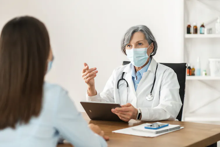 A doctor talking to a female patient, both wearing face masks