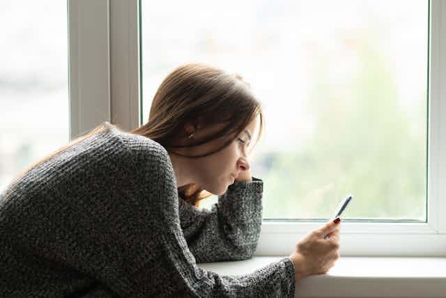 A young women looks at her smartphone.