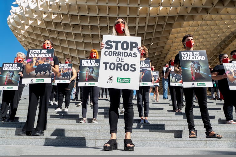 Los manifestantes se paran frente a una plaza de toros y sostienen pancartas que piden el fin de las corridas de toros.