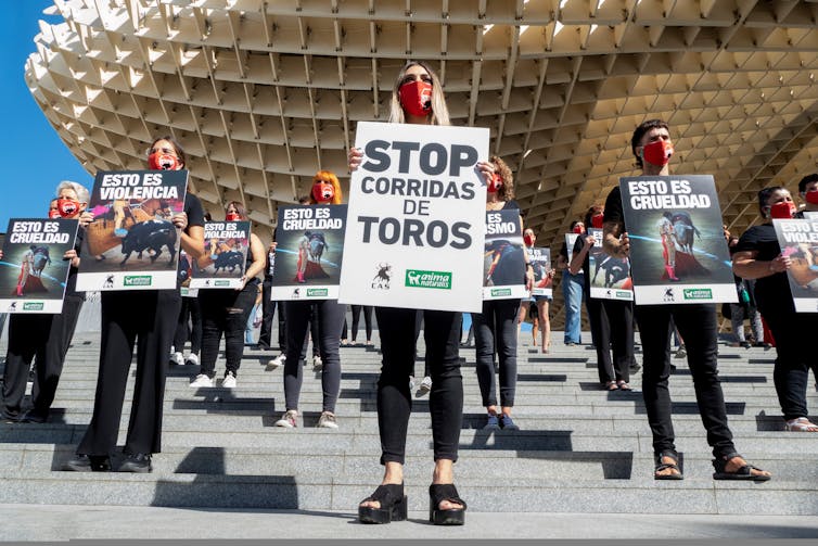 Protestors stand outside a bullfighting ring hold placards calling for an end to bullfighting.