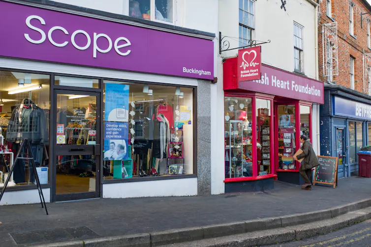 Charity shops next to each other on a UK high street.
