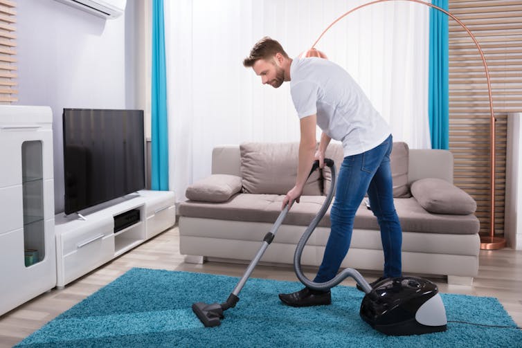 A man vacuums his house.