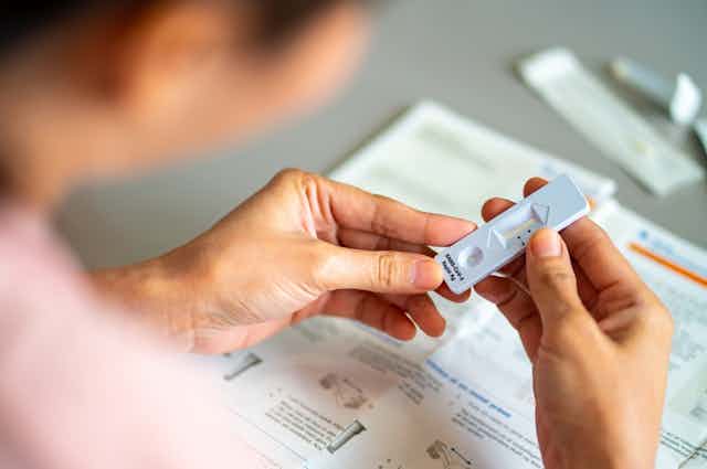 Person holding rapid antigen test, reading instructions