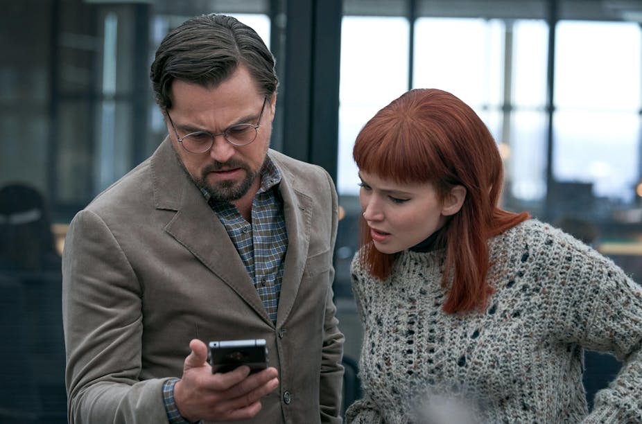 DiCaprio and Lawrence look at cell phone in a still from the movie.