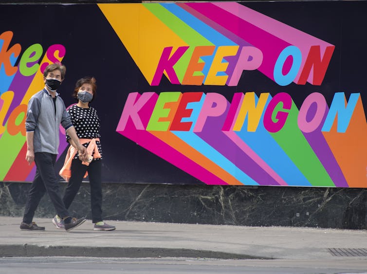 A couple walk past an inspiring and colorful mural that reads 'Keep Going'