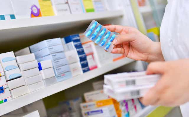 A pharmacist selecting antibiotics rom a shelf