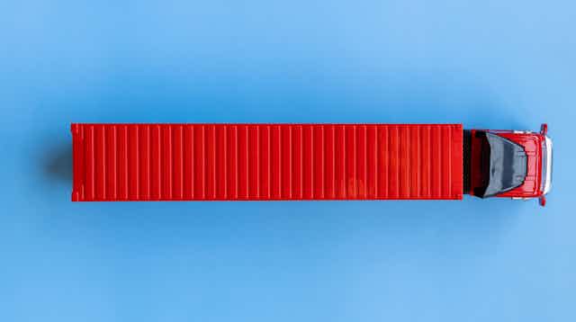 A big red lorry against a blue background, seen from above.