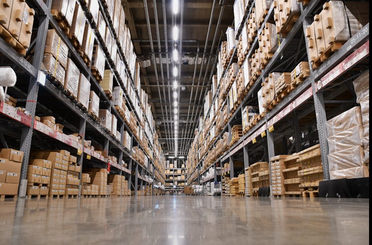 An aisle in a warehouse with shelves stacked with boxes