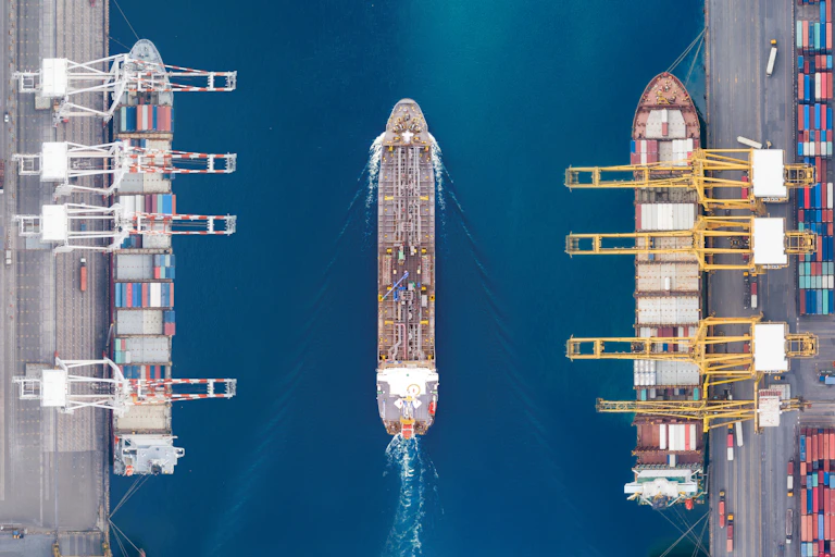 Aerial view of a ship moving through a port.