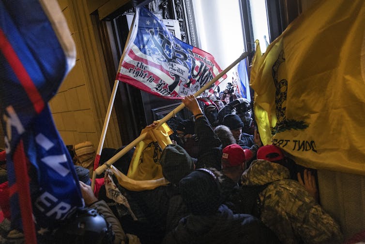 Rioters bearing flags breaking into the Capitol building