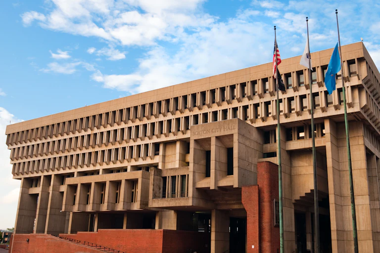 Three flags stand in front of Boston City Hall.
