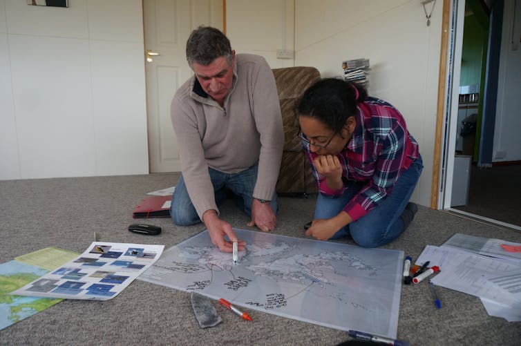 Two people examine an annotated map of the Falkland Islands