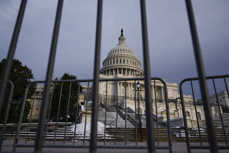 A view of the U.S. capitol building through security fencing in front of it.