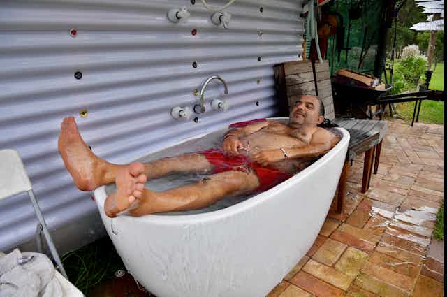 man reclines in outdoor bath