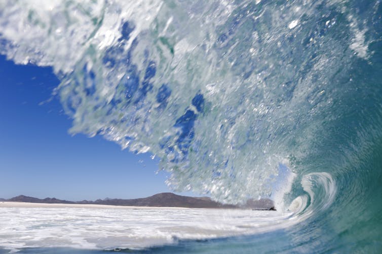 Ocean wave with land in background