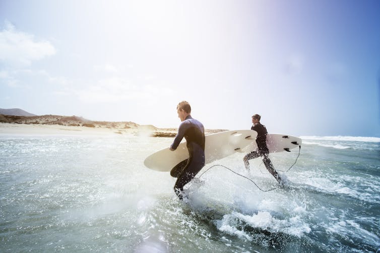 Two men running in from surfing