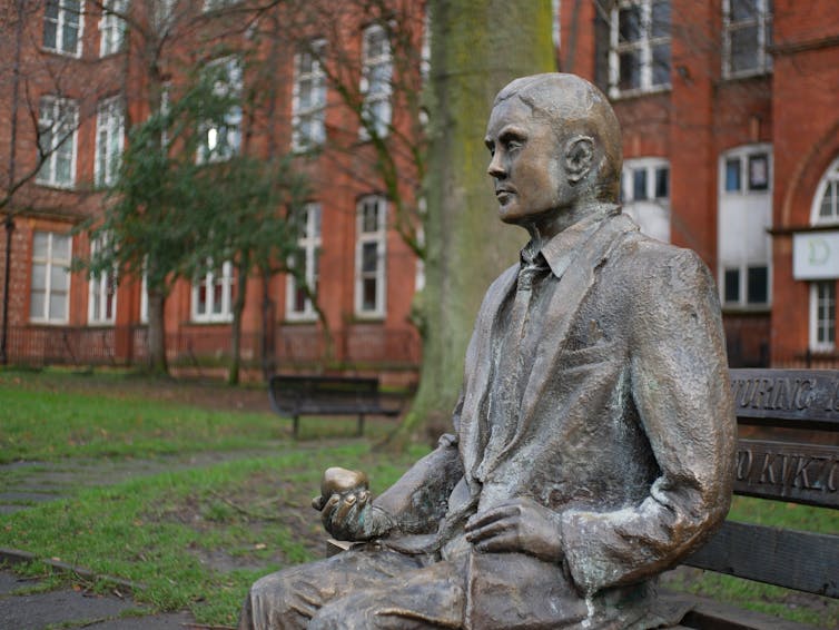 A bronze statue of Alan Turing sitting on a bench in Manchester