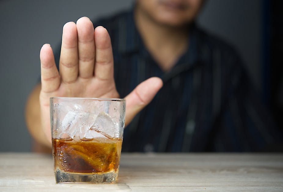 Un homme refuse d'un geste de la main un verre d'alcool