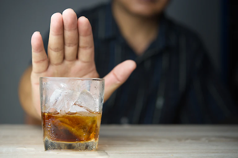 Un homme refuse d'un geste de la main un verre d'alcool
