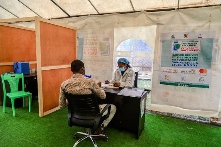 Un homme vient se faire vacciner contre le Covid-19, à Yaoundé, il est assis de dos face au médecin