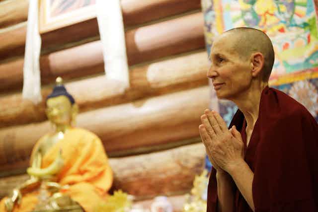 A fully ordained Buddhist nun bows to other residents and guests during morning mediation.