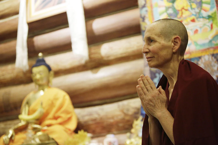 A fully ordained Buddhist nun bows to other residents and guests during morning mediation.