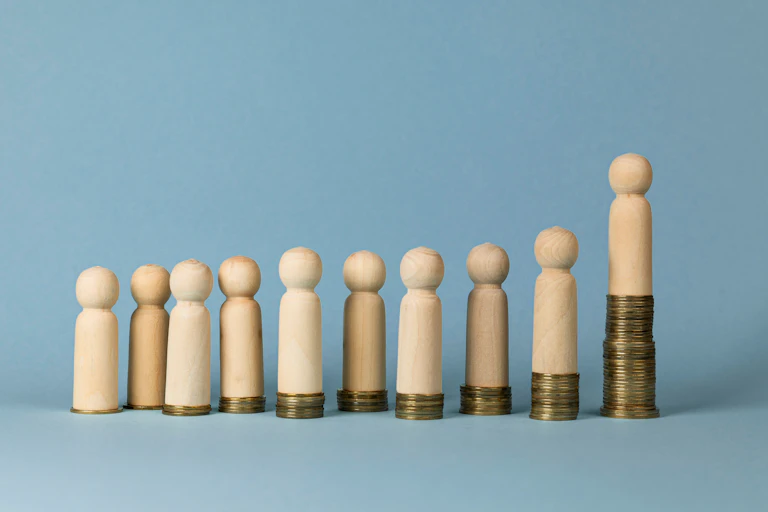 Wooden figures standing on coin stacks of varying size.