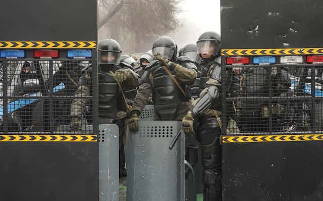 Kazakhstani security forces wearing full riot gear block a street in the capital Almaty