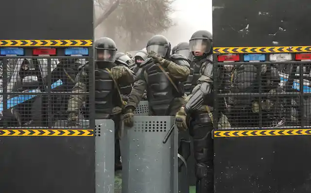 Kazakhstani security forces wearing full riot gear block a street in the capital Almaty