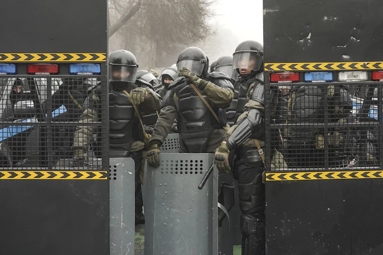 Kazakhstani security forces wearing full riot gear block a street in the capital Almaty