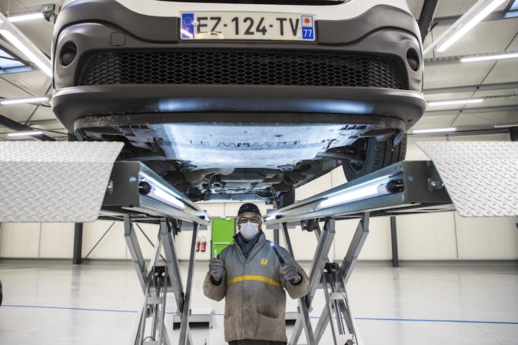Factory worker underneath a car