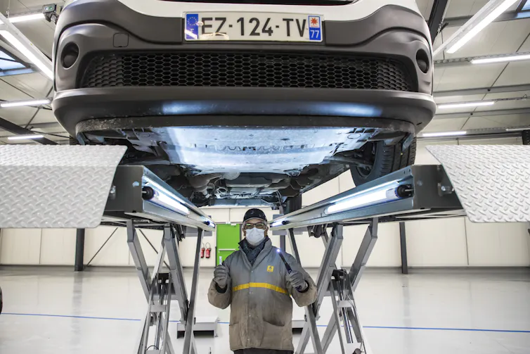 Factory worker underneath a car