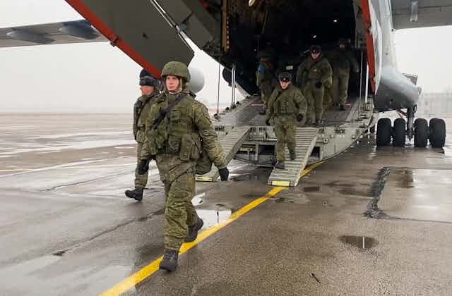 Soldiers march off an airplane