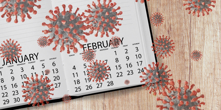 A calendar against a woodgrain background superimposed with coronaviruses