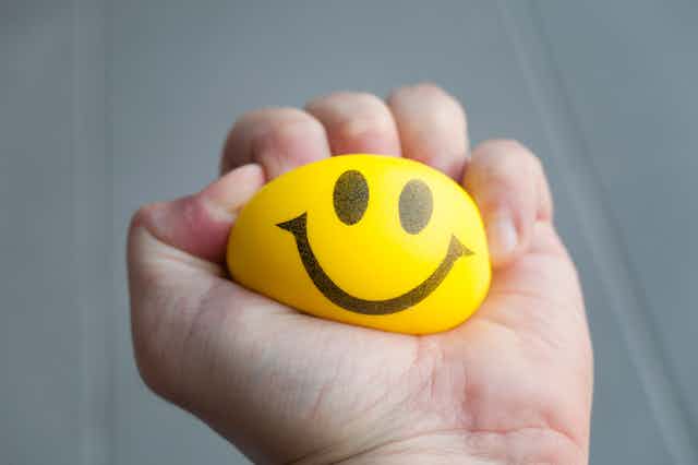A smiley stress ball being squeezed