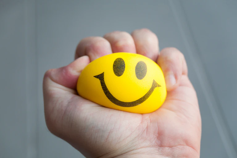 A smiley stress ball being squeezed