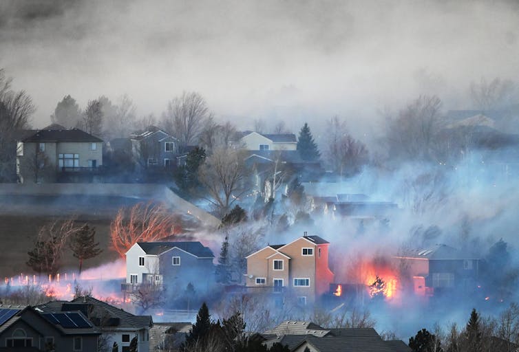 Fire moves through a neighborhood, burning around one house and into another.