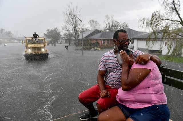 A man comforts a woman in the back of a rescue truck on a flooded street in Louisiana