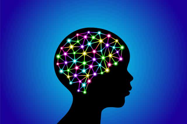 Silhouette of the side profile of a human head with multicolored glowing connected dots in the shape of a brain.